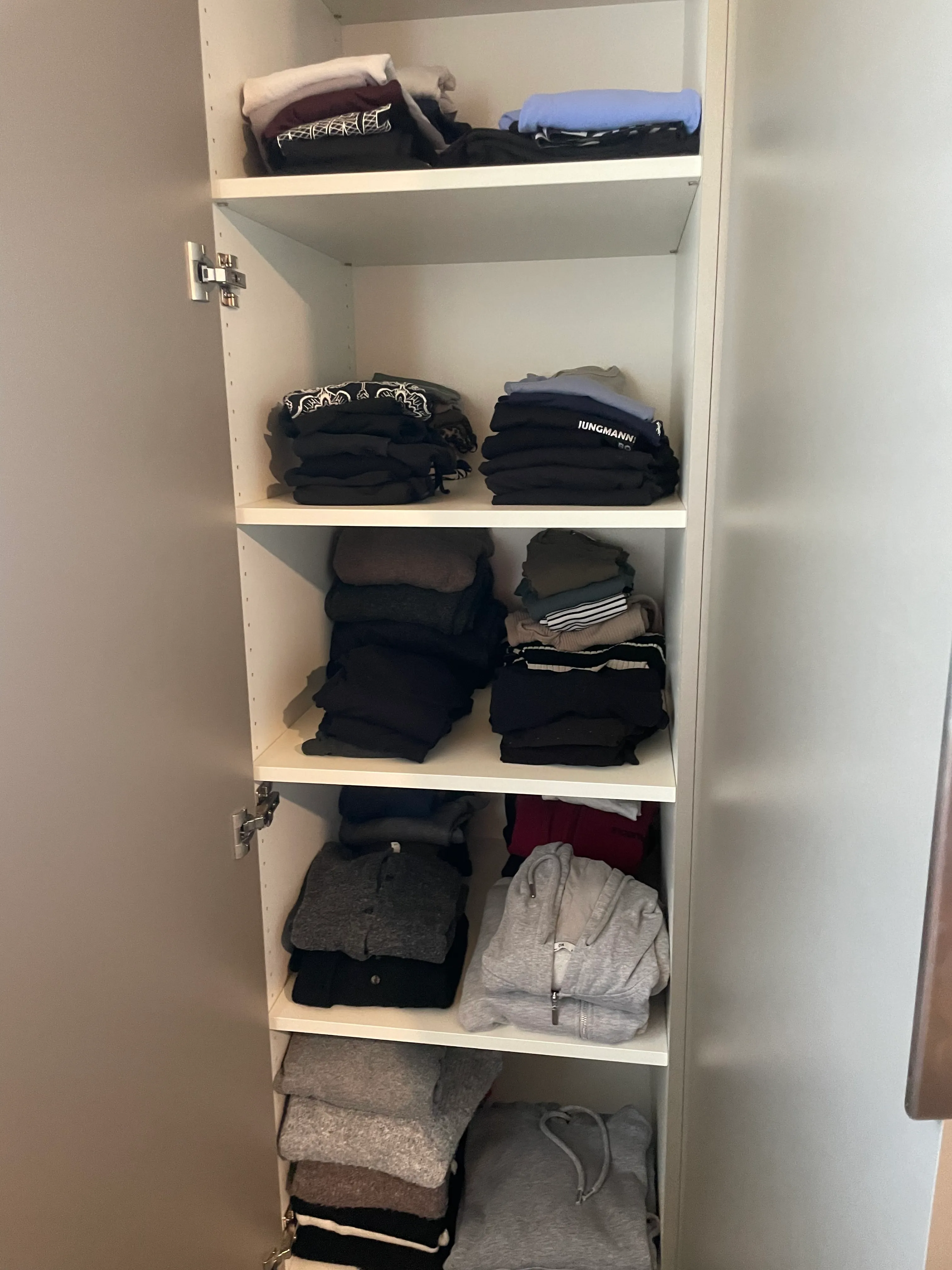Offener kleiner Kleiderschrank, Fächer aufgeräumt.